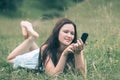 Attractive young woman using her smartphone while lying in a clearing Royalty Free Stock Photo