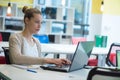 Attractive young woman using laptop while sitting at her desk. Young american businesswoman sitting in the office and working on Royalty Free Stock Photo