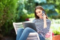 Attractive young woman using mobile phone and laptop while sitting on the balcony at home Royalty Free Stock Photo