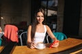 Attractive young woman using phone in cafe on terrace. Social distancing. Beautiful brunette girl chatting and drink Royalty Free Stock Photo