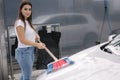 Attractive young woman washing her car with shampoo and brushes. Female washes automobile with foam and water outside on Royalty Free Stock Photo