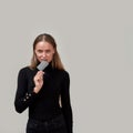 Attractive young woman wearing black clothes looking playful, holding plastic credit card in her mouth while posing