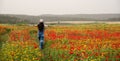 Attractive young woman wearing red dress walking happy in poppy flower spring field. Royalty Free Stock Photo