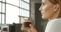 Attractive young woman wearing a white sweater in a loft style bakery or coffee shop with an ice latte Royalty Free Stock Photo