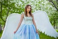 woman in a white corset and a blue puffy dress with large white angel wings behind her back