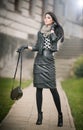 Attractive young woman in a winter fashion shot. Beautiful fashionable young girl in black leather outfit posing on avenue