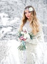 Attractive young woman in winter snow forest outdoors with flowers on her head and bouquet Royalty Free Stock Photo