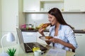 Young woman working with laptop computer and documents while sitting at the kitchen Royalty Free Stock Photo