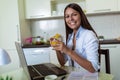 Young woman working with laptop computer and documents while sitting at the kitchen Royalty Free Stock Photo