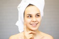 Attractive Young Woman Wrapped with Bath Towels, Applying Cream on her Face After a Shower at the Bathroom Royalty Free Stock Photo