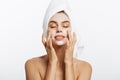 Attractive Young Woman Wrapped with Bath Towels, Applying Cream on her Face After a Shower at the Bathroom. Royalty Free Stock Photo