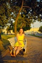 Attractive young woman in yellow dress, sitting in a summer park on a bench Royalty Free Stock Photo