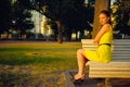 Attractive young woman in yellow dress, sitting in a summer park on a bench Royalty Free Stock Photo