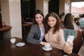 Attractive young women making selfie in restairant. Women drin cappuccino on terrace. Two female make photo together Royalty Free Stock Photo