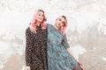 Attractive young women with pink hair in black and blue dresses with vintage stylish floral pattern stand and hug near vintage Royalty Free Stock Photo