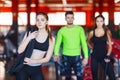 An attractive young woman standing in a fitness center posing with a physical rope over her shoulder.