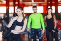 An attractive young woman standing in a fitness center posing with a physical rope over her shoulder.