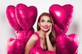 Attractiveyoung woman with pink heart balloons on white background
