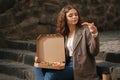 Attrative woman open pizza box and eating vegan pizza outdoors