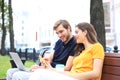 Attrative young couple sitting on a bench and looking something in mobile phone Royalty Free Stock Photo