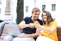 Attrative young couple sitting on a bench and looking something in mobile phone Royalty Free Stock Photo