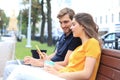 Attrative young couple sitting on a bench and looking something in mobile phone Royalty Free Stock Photo
