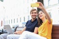 Attrative young couple sitting on a bench and taking selfie on smartphone Royalty Free Stock Photo