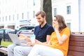 Attrative young couple using laptop computer while sitting on a bench outdoors Royalty Free Stock Photo