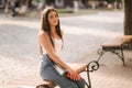 Attrective brunette sitting alone on the bench in centre of the city. Beautiful young woman drinking coffe outdoors. End Royalty Free Stock Photo