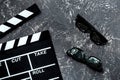 Attributes of film director. Movie clapperboard and sunglasses on grey stone table background top view
