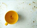 Attrition still life, empty yellow ceramic mug of tea cup on worn dirty stained white board, top view with copy space Royalty Free Stock Photo