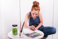 Atttractive redhead is painting with water colours Royalty Free Stock Photo