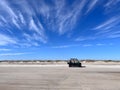 An ATV sits on the sand of a beach on the Outer Banks of North Carolina under a blue sky with streak of clouds Royalty Free Stock Photo