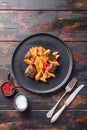 Aubergine penne eggplant pasta, pepper tomatoe sauce, on black plate over old dark wooden table served top view Royalty Free Stock Photo