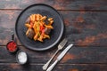 Aubergine penne eggplant pasta, pepper tomatoe sauce, on black plate over old dark wooden table served top view space for text Royalty Free Stock Photo