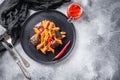 Aubergine penne eggplant pasta, pepper tomatoe sauce, on black plate overgrey concrete background  served top view space for text Royalty Free Stock Photo