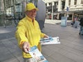 AUCKLAND, NEW ZEALAND - Aug 24, 2019: Falun Gong (Dafa) smiling man in yellow jacked distributes leaflets in Queen Street