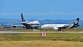 Air New Zealand Airbus A320 taxiing while Singapore Airlines Boeing 747-400 freighter takes off at Auckland International Airport Royalty Free Stock Photo