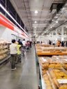 Customers lining up inside Costco to purchase cooked rotisserie chickens.