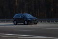 Audi black rides on the road. Against a background of blurred trees