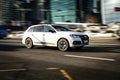 Audi Q7 3.0 TFSI at the test drive on city street. White SUV rushing on urban road