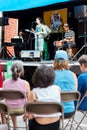 The audiance is watching a local jazz band concert on an outdoor stage