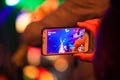 Audience capturing the performance of an artist, while on the stage, using her phone camera Royalty Free Stock Photo