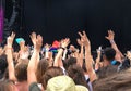 Audience with hands raised at a music festival, empty stage with copy space