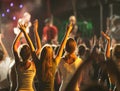 Audience with hands raised at a music festival and lights streaming down from above the stage. Royalty Free Stock Photo