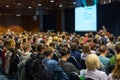 Audience in lecture hall participating at business event.