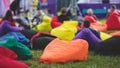 Audience at the open air venue listens to lecturer, people on a bean bags together listen to speaker on stage at master-class,