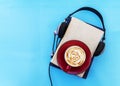 Audio book concept. Black headphones with books and cup of fresh coffee on blue background. Top view. copy space Royalty Free Stock Photo