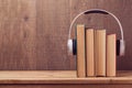 Audio books concept with old books and headphones over wooden background Royalty Free Stock Photo