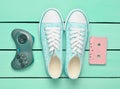 Audio cassette, gamepad, sneakers shoes on a turquoise pastel background.